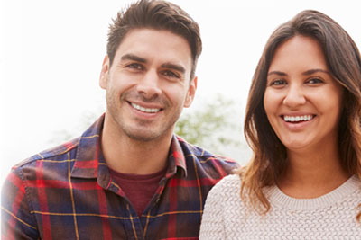 Happy man and woman showcasing their healthy smiles.