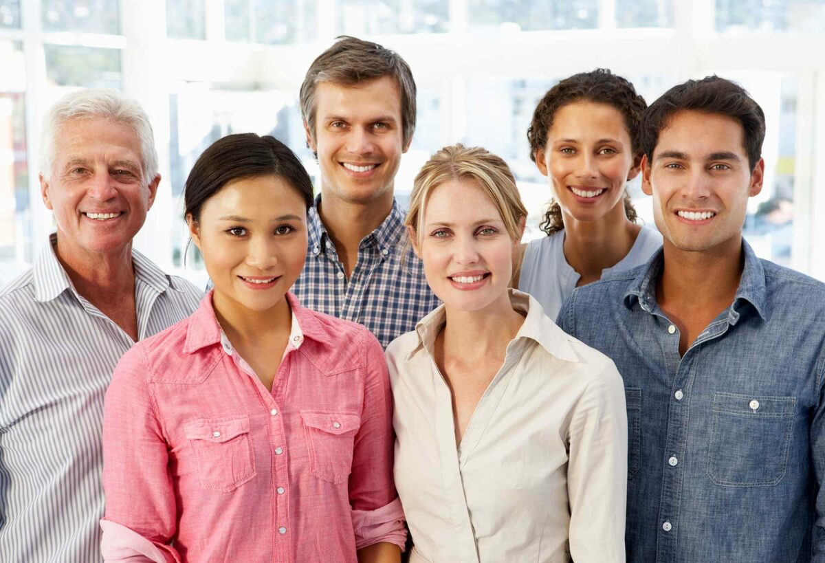 Group of happy individuals standing together for a group photo, all showcasing healthy smiles.